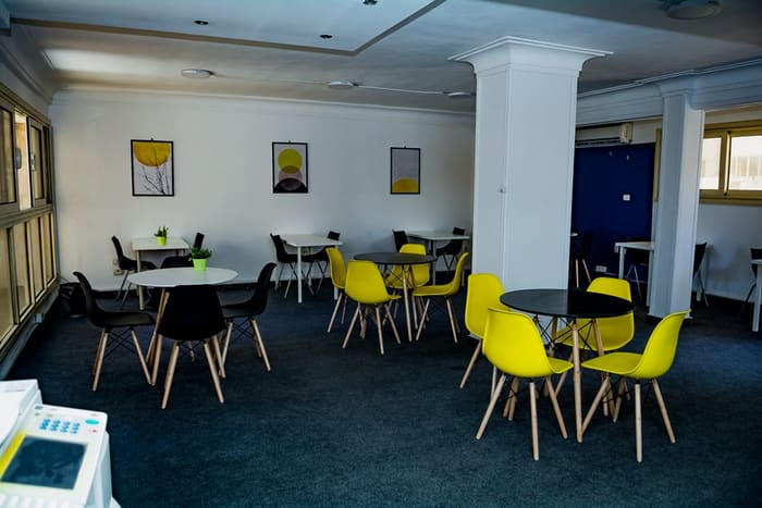 Breakout lounge at Blooms with round tables, yellow chairs and daylight