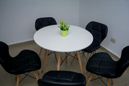Round white meeting table with four upholstered chairs for small sessions at Blooms