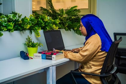 A member working at a dedicated desk beside the planted ledge at Blooms