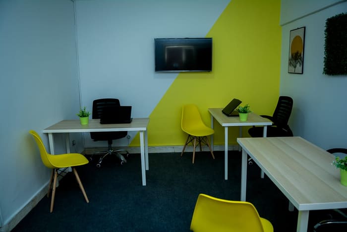 A furnished private office suite at Blooms with desks, a wall display and a lime accent wall