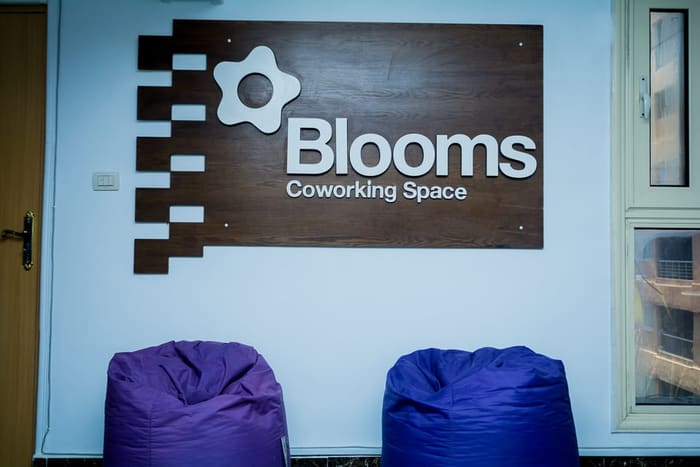 The Blooms Coworking Space reception sign above purple lounge seating
