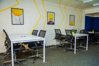 Open shared workspace floor at Blooms with white desks and a yellow graphic wall