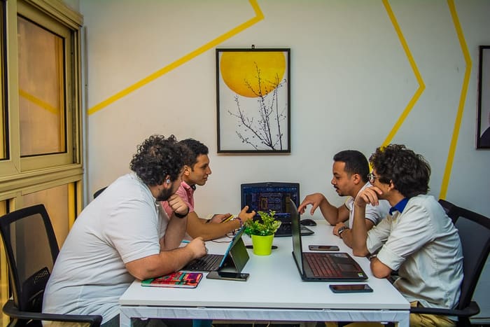 A team of four collaborating over laptops at a table in the Blooms meeting room